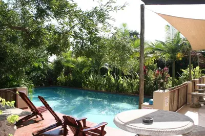 a swimming pool with two chairs and a table at Villa Royal Palm in Komatipoort
