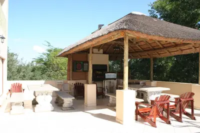 a pavilion with chairs and tables and a thatch roof at Villa Royal Palm in Komatipoort