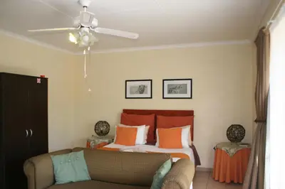 a bedroom with a bed and a couch at Villa Royal Palm in Komatipoort