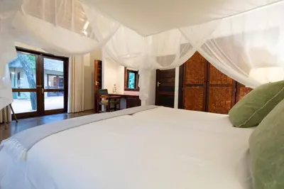 a bedroom with a white bed with a white canopy at Kingly Bush Villa in Phalaborwa