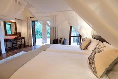 a large white bed in a room with a window at Kingly Bush Villa in Phalaborwa