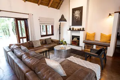 a living room with a leather couch and a table at Kingly Bush Villa in Phalaborwa