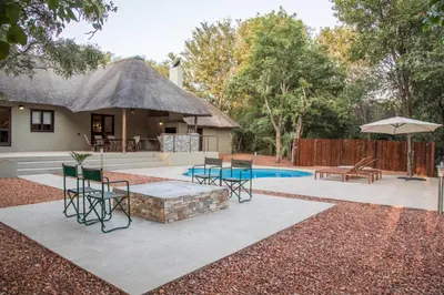 a patio with a table and chairs and a house at Kingly Bush Villa in Phalaborwa