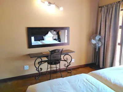 a bedroom with a desk and a tv on the wall at Zebula Luxury Lodge in Mabula