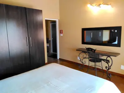 a bedroom with a bed and a desk and a tv at Zebula Luxury Lodge in Mabula
