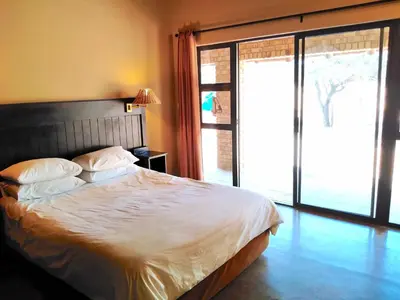 a bedroom with a bed and a large sliding glass door at Zebula Luxury Lodge in Mabula
