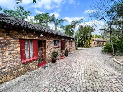 a brick building with red doors and a brick driveway at Masasana’s Rest in Hazyview