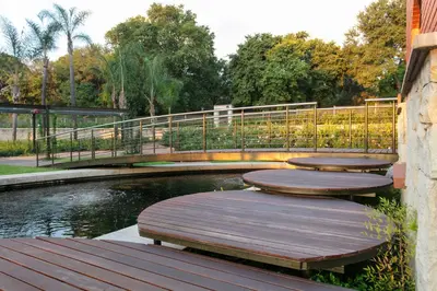 a bridge over a pond with three wooden benches at The Rasmus in Pretoria