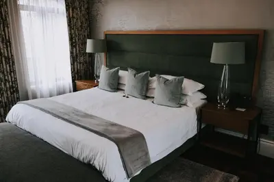 a bedroom with a large white bed with a green headboard at The Rasmus in Pretoria