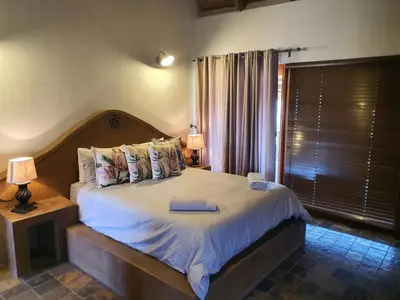 a bedroom with a bed with two lamps and a window at Hadeda Lodge, Mabalingwe in Warmbaths