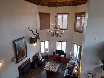 a living room with a fireplace and a chandelier at Hadeda Lodge, Mabalingwe in Warmbaths