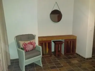 a room with a chair and a table and a mirror at Hadeda Lodge, Mabalingwe in Warmbaths