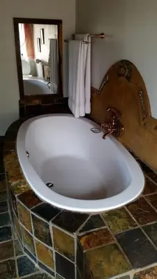 a large bath tub in a bathroom with a mirror at Hadeda Lodge, Mabalingwe in Warmbaths