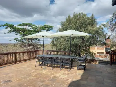 a table and chairs with umbrellas on a deck at Hadeda Lodge, Mabalingwe in Warmbaths