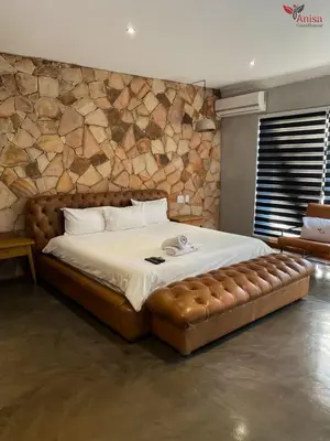 a bedroom with a large bed with a brown tufted bedskirts at ANISA GUESTHOUSE in Thohoyandou