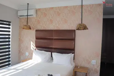 a bedroom with a bed with white pillows and two lights at ANISA GUESTHOUSE in Thohoyandou