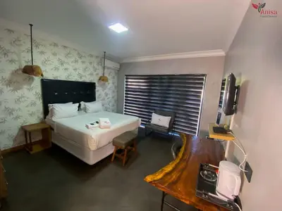 a bedroom with a large white bed and a television at ANISA GUESTHOUSE in Thohoyandou