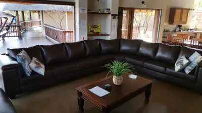 a brown leather couch in a living room with a table at Kanaan, Mabalingwe in Mabula