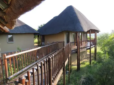 a building with a thatch roof and a wooden deck at Kanaan, Mabalingwe in Mabula