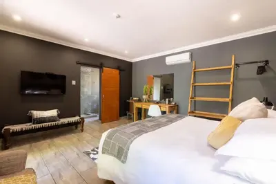 a bedroom with a large white bed and a desk at Lowveld Living Guesthouse in Nelspruit