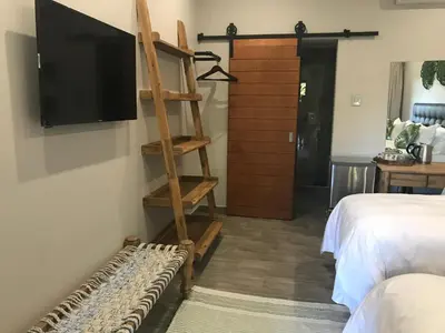 a room with a tv and a ladder and a bed at Lowveld Living Guesthouse in Nelspruit