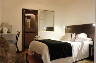 a bedroom with a bed with a black blanket and a mirror at Francor Guesthouse in Pretoria