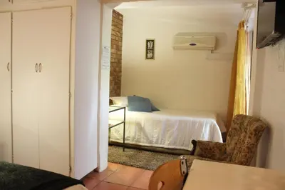 a bedroom with a bed and a table in a room at Francor Guesthouse in Pretoria
