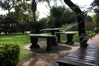 three picnic tables in a park with a lawn at Francor Guesthouse in Pretoria