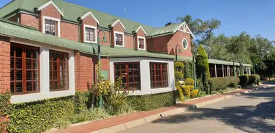 a red brick building with a green roof at Pietersburg Club in Polokwane