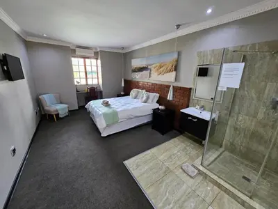 a bedroom with a bed and a glass shower at Pietersburg Club in Polokwane