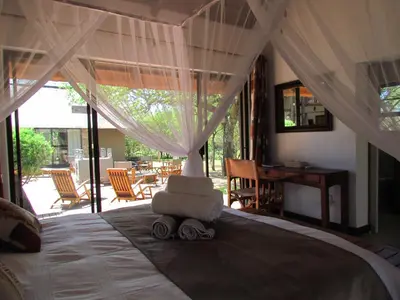 a bedroom with a bed with a chair on it at Swiblati Lodge in Hoedspruit