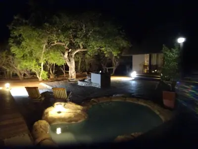 a swimming pool in the middle of a yard at night at Swiblati Lodge in Hoedspruit