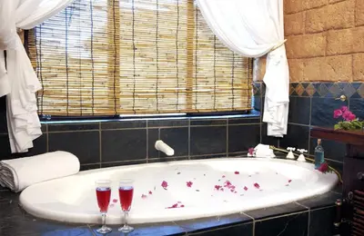 two wine glasses sitting on a tub in a bathroom at Zwahili Private Game Lodge & Spa in Modimolle