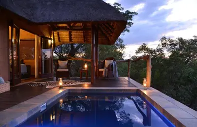 a swimming pool with an umbrella and a house at Zwahili Private Game Lodge & Spa in Modimolle