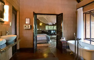 a bathroom with a tub and a bedroom with a bed at Zwahili Private Game Lodge & Spa in Modimolle