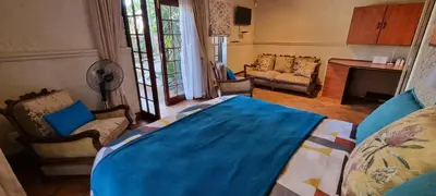 a bedroom with a blue bed and a living room at Casabac in Pretoria