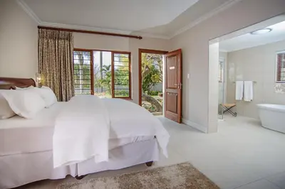 a white bedroom with a bed and a tub and a shower at Indalo Leaves Lodge and Spa in Nelspruit