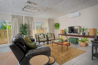 a living room with a leather couch and a tv at Indalo Leaves Lodge and Spa in Nelspruit