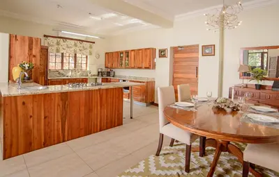 a kitchen with wooden cabinets and a wooden table at Indalo Leaves Lodge and Spa in Nelspruit