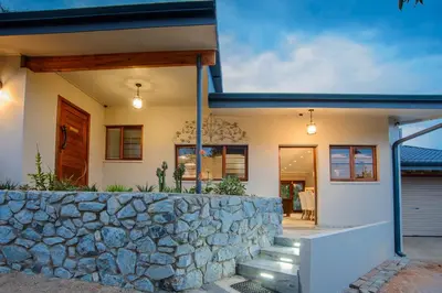 a house with a stone wall in front of it at Indalo Leaves Lodge and Spa in Nelspruit