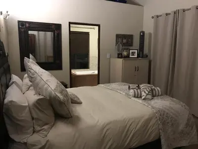 a bedroom with a bed with pillows and a mirror at Twenty Four Mabalingwe Nature Reserve in Mabula