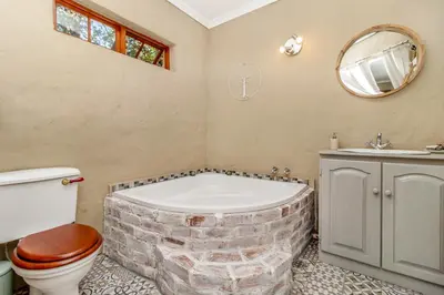 a bathroom with a brick tub and a toilet and a sink at Villa Roma - Luxury Accommodation in Centurion