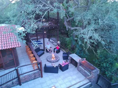 a man and woman sitting around a fire in a yard at Peace@Kruger in Marloth Park