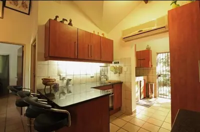 a kitchen with wooden cabinets and bar stools at Peace@Kruger in Marloth Park