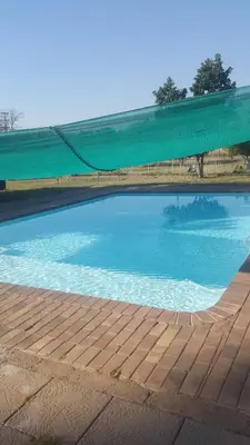 a large swimming pool with a green tarp around it at Aruka in Bela-Bela