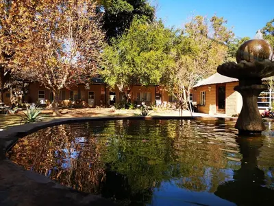 a fountain in the middle of a pond in front of a building at Aruka in Bela-Bela