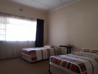 two beds in a room with a window at Aruka in Bela-Bela