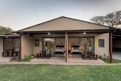 a small house with glass doors with beds in it at Kiyala Guest Farm in Nelspruit