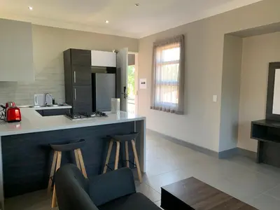 a kitchen with a counter and two bar stools at Hotel AT Hatfield Apartments in Pretoria