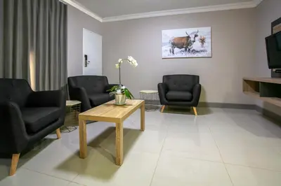 a waiting room with chairs and a table and a television at Hotel AT Hatfield Apartments in Pretoria